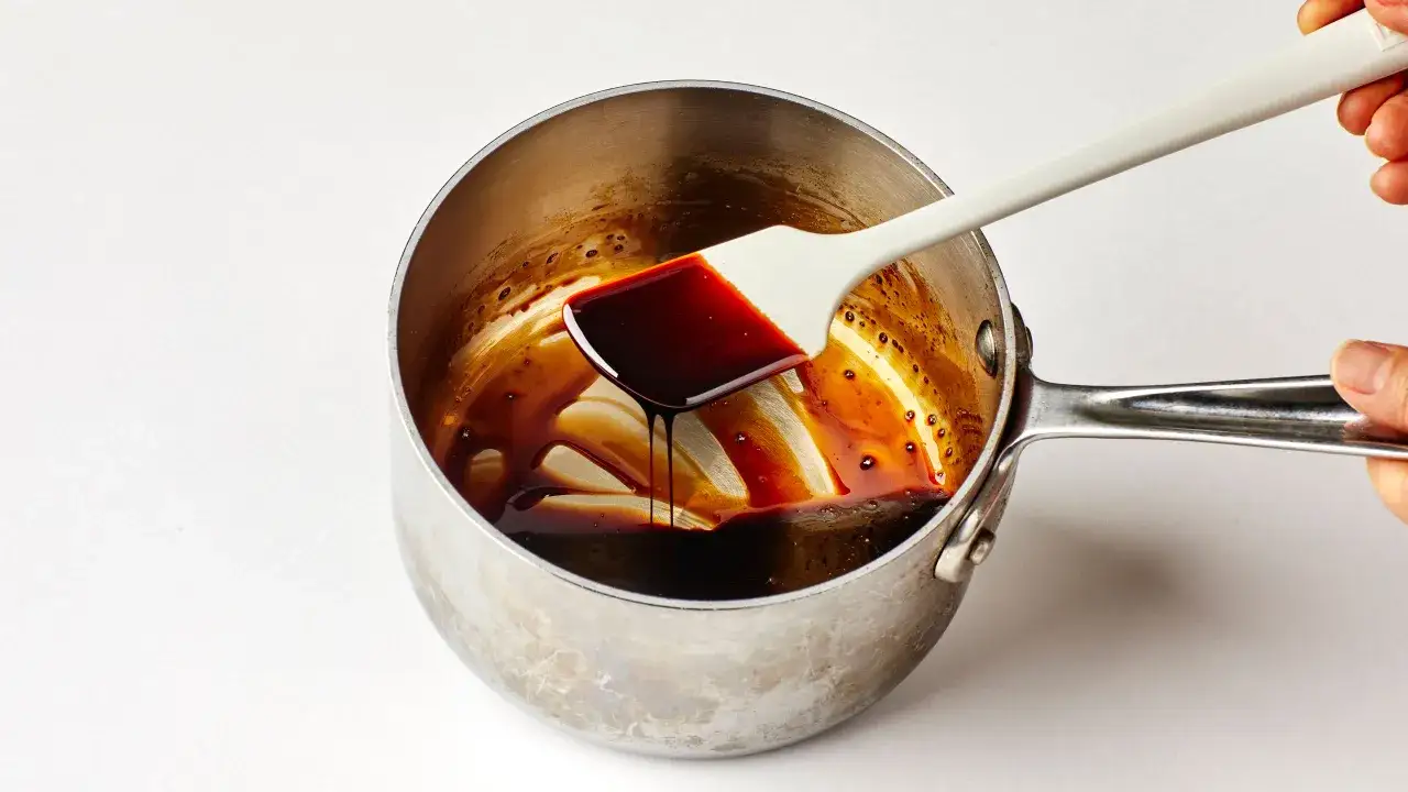 Balsamiczny sos redukuje się w rondelku, a biała łopatka nabiera jego gęstą, ciemną konsystencję.