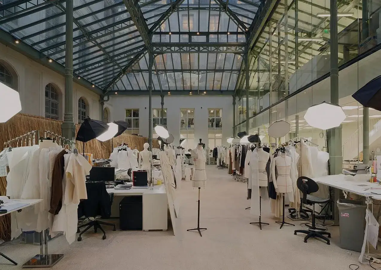 Laboratorio di moda con manichini, abiti appesi e luci, dove un visual designer dà vita alle sue idee.
