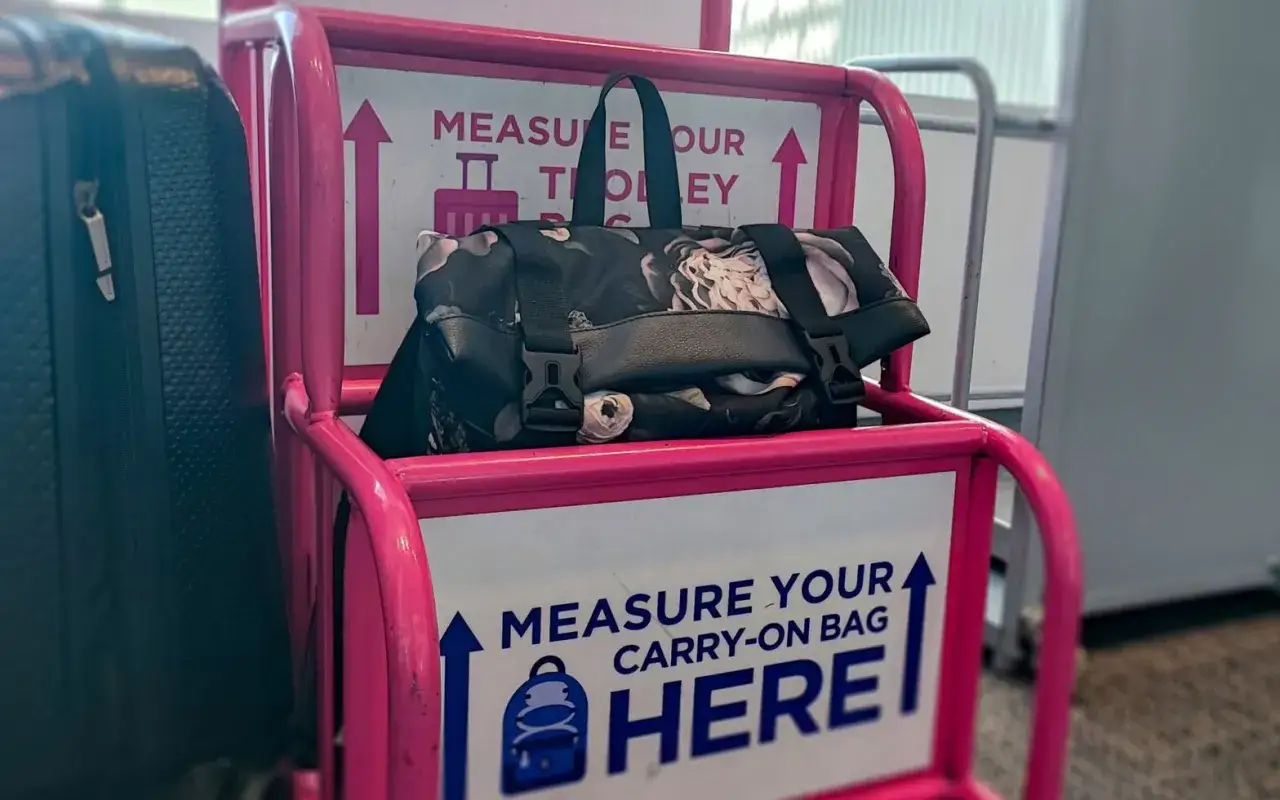 Torba z kwiatowym wzorem na wózku do mierzenia bagażu podręcznego American Airlines.