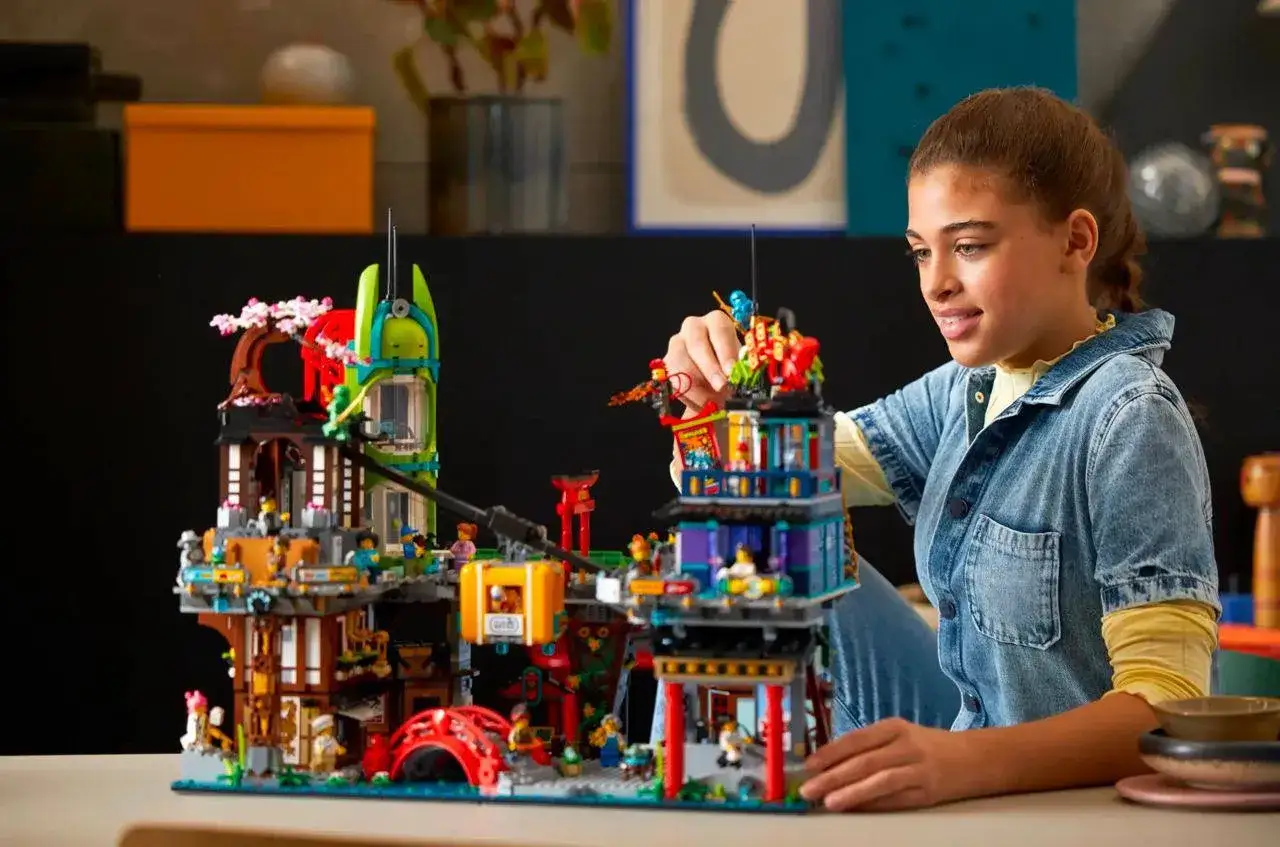 Dziewczynka buduje skomplikowany zamek z klock&oacute;w LEGO, inspirując się pomysłami na budowle.