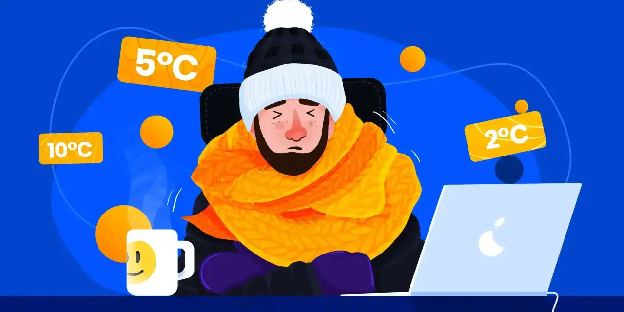 Zimno w pracy! Mężczyzna w czapce i szaliku marznie przy laptopie. Wokół tabliczki z niską temperaturą: 10°C, 5°C, 2°C.