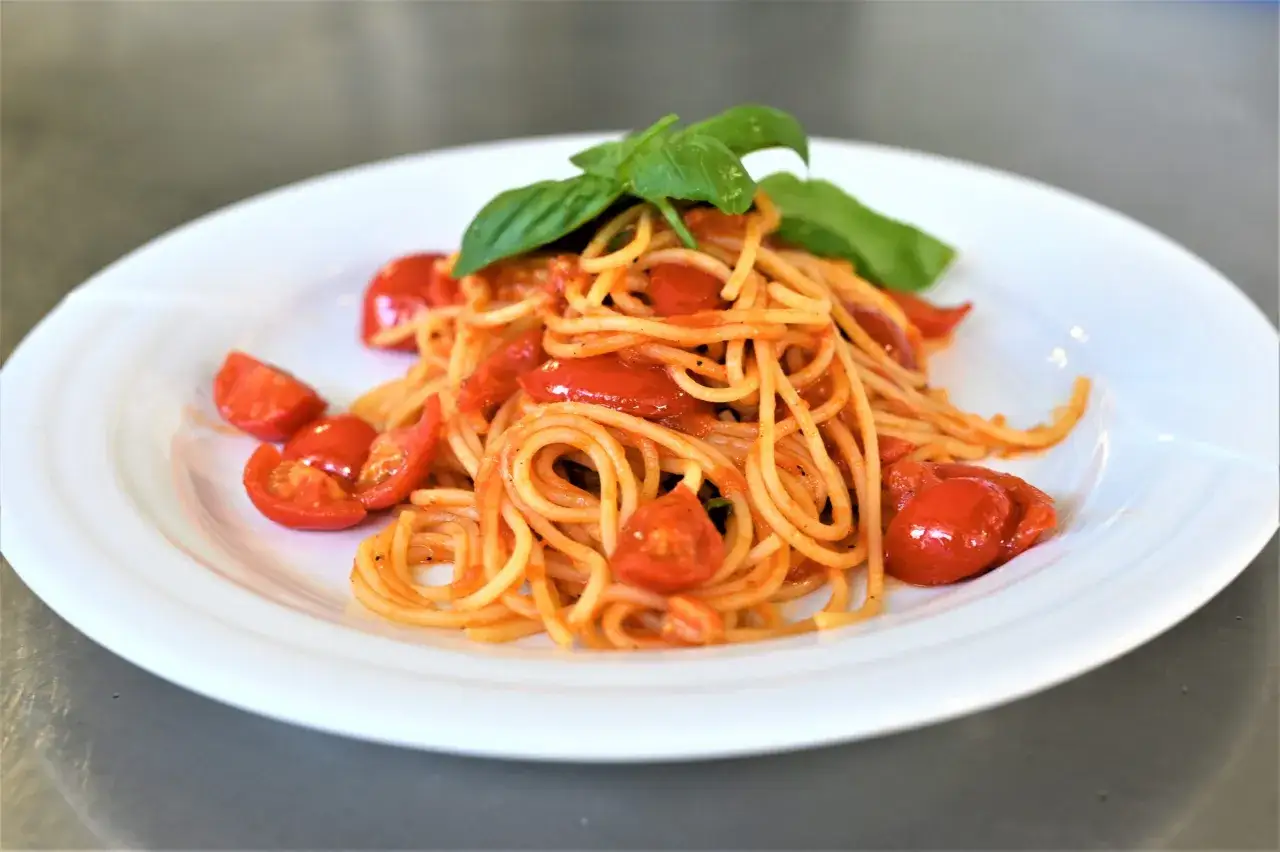 Un piatto di spaghetti al pomodoro fresco, conditi con pomodorini succosi e basilico profumato.