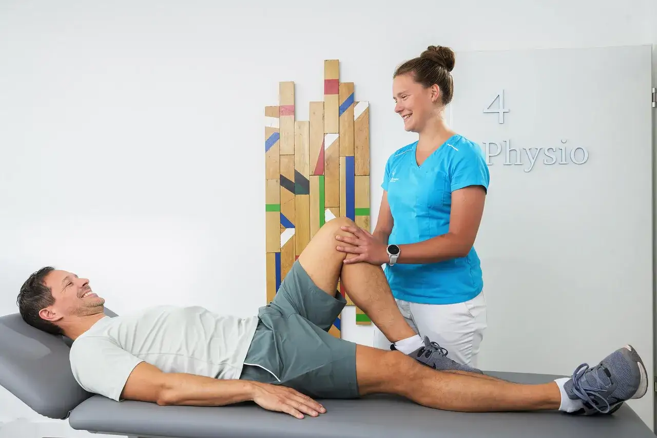 Physiotherapeutin beugt das Knie eines Mannes auf einer Liege. Ein Beispiel f&uuml;r den Unterschied zwischen manueller Therapie und Physiotherapie.