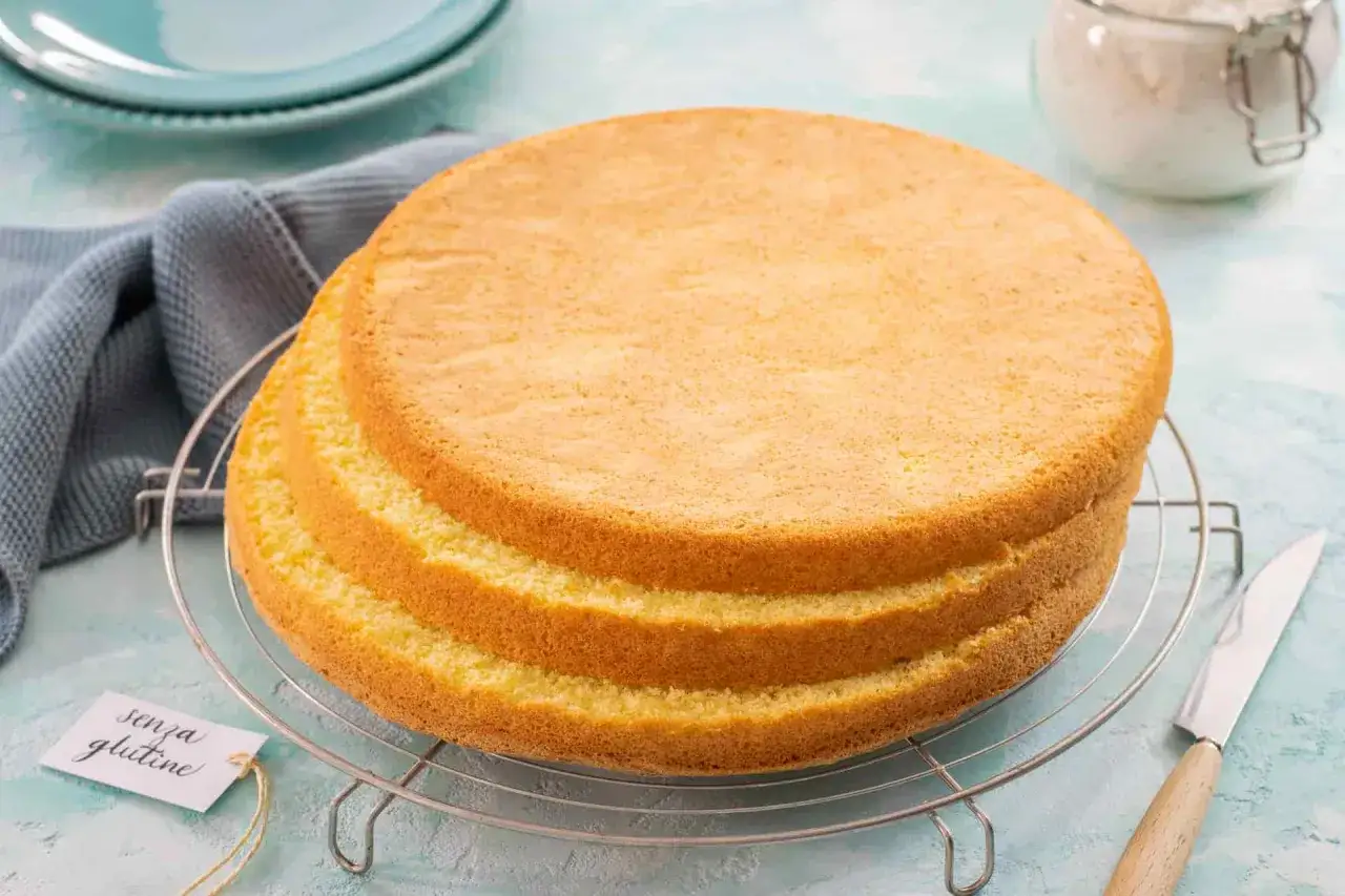 Tre soffici strati di pan di spagna senza glutine raffreddano su una griglia. Perfetto per torte leggere e deliziose.