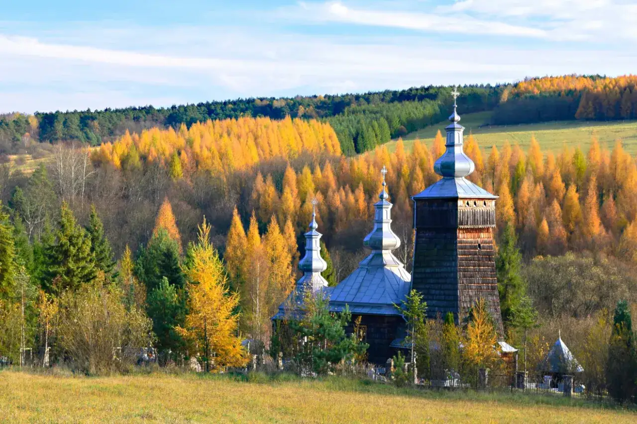 Drewniana cerkiew na tle jesiennych kolorów Beskidu Niskiego.