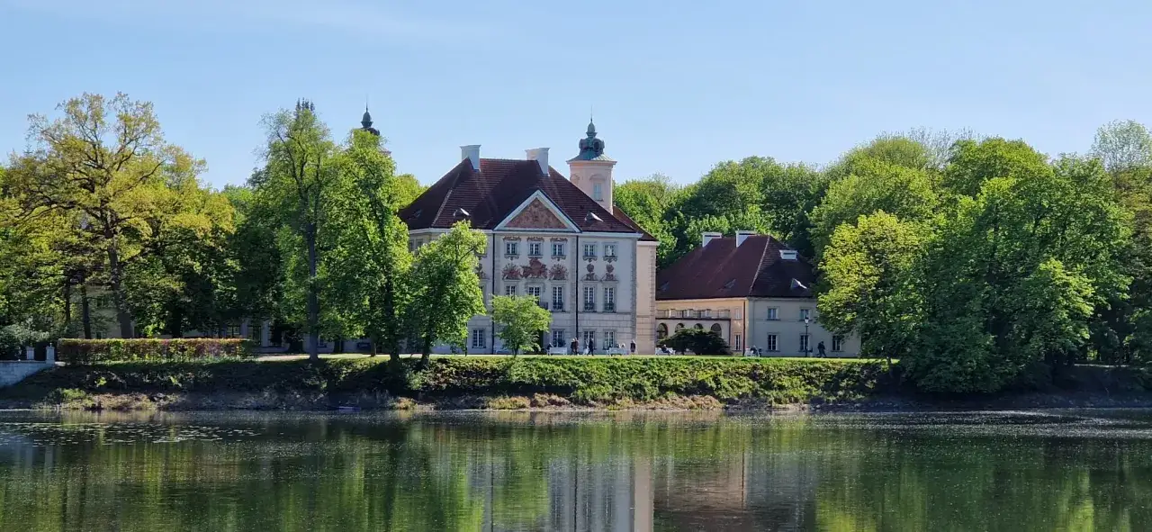 Pałac otoczony zielenią nad spokojnym jeziorem Rokola.