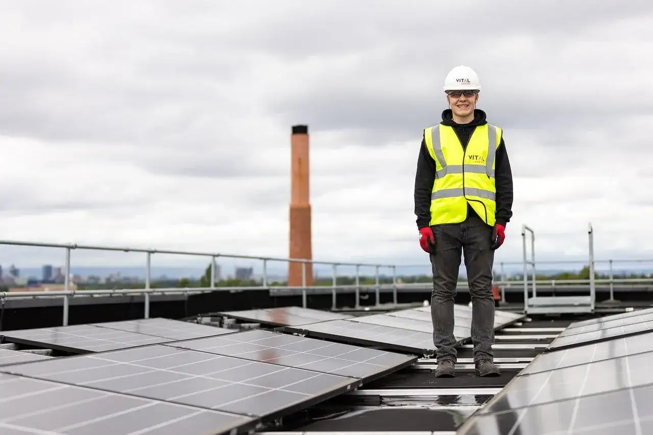 Pracownik na dachu z panelami słonecznymi. Uważaj na oszust&oacute;w Columbus Energy, kt&oacute;rzy obiecują zieloną energię, a dostarczają problemy.