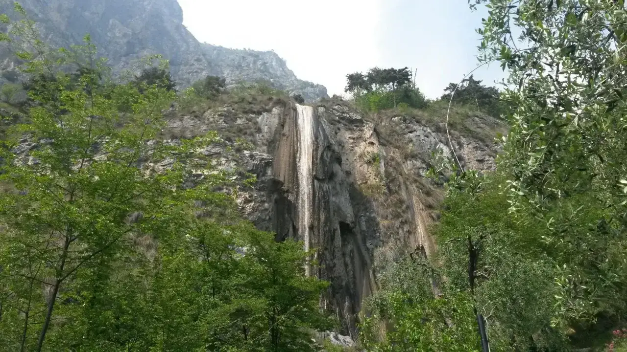 Cascata del Sopino, un velo d'acqua scende da una parete rocciosa circondata da vegetazione lussureggiante.
