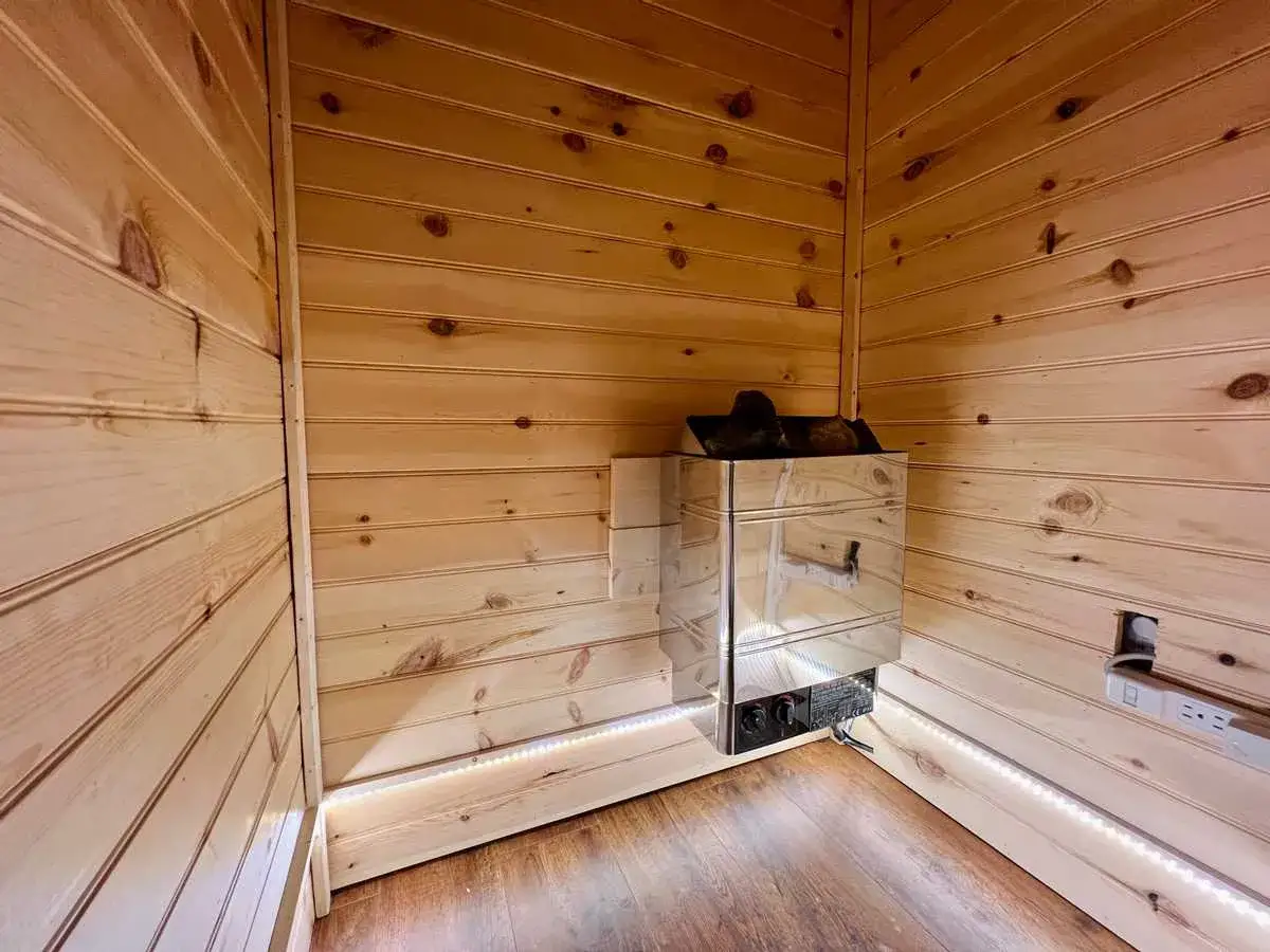 Drewniana sauna z błyszczącym piecem i dyskretnym oświetleniem LED. Idealne miejsce, by dowiedzieć się, jak zbudować saunę.