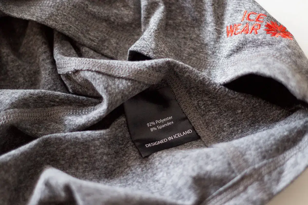 Szara koszulka z metką: 92% poliester, 8% spandex. To materiał poliamidowy, idealny na odzież sportową.
