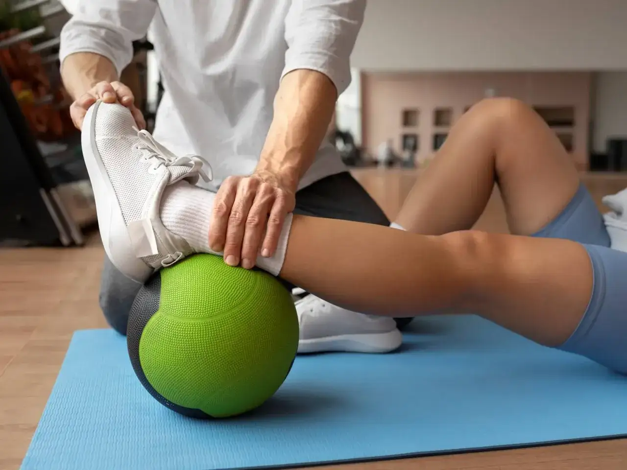 Fizjoterapeuta pomaga sportowcowi w ćwiczeniach z piłką lekarską, kluczowy element fizjoterapii sportowej.