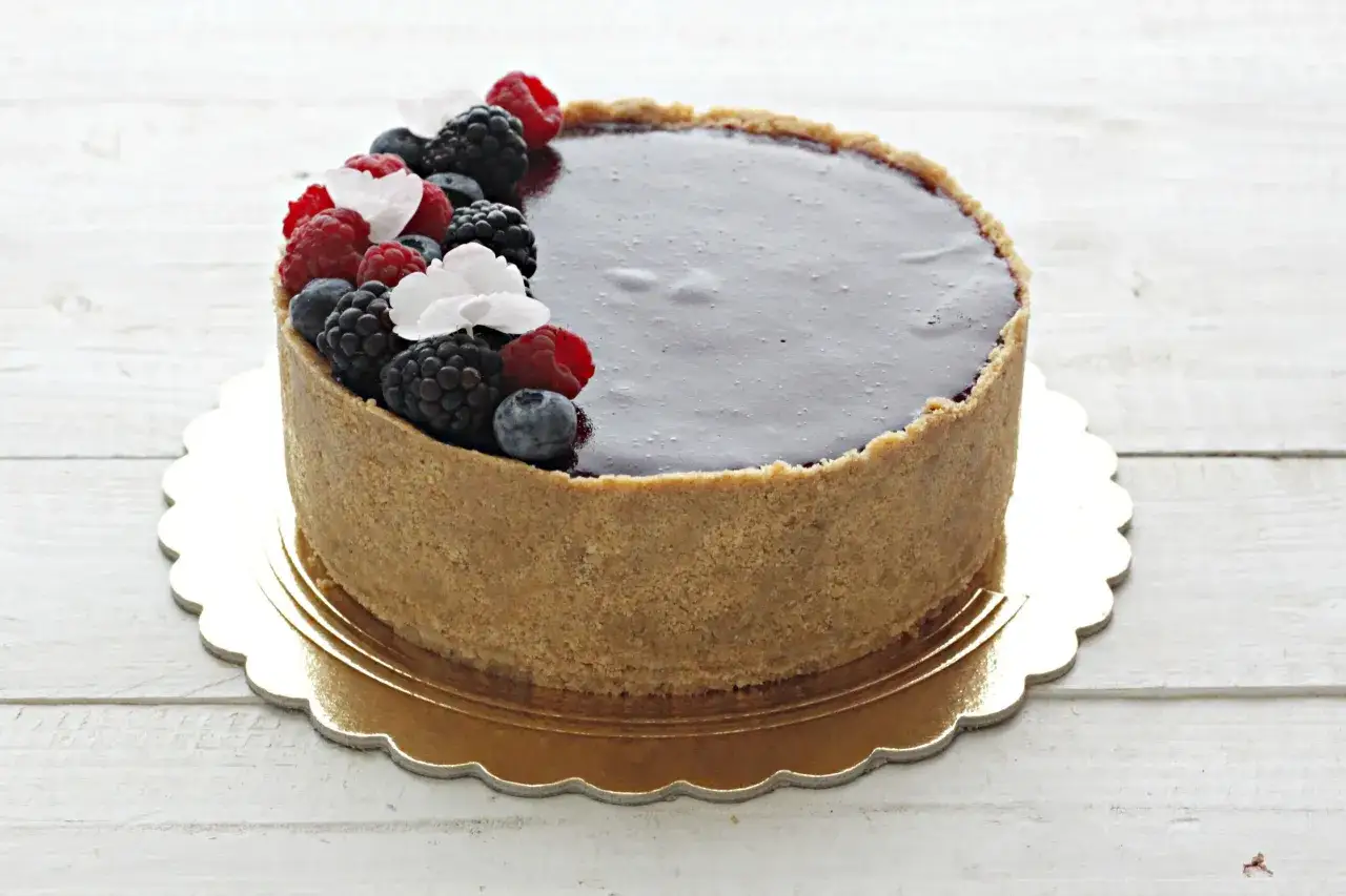 Cheesecake con mascarpone e frutti di bosco, una delizia cremosa con una crosta croccante e una copertura lucida.
