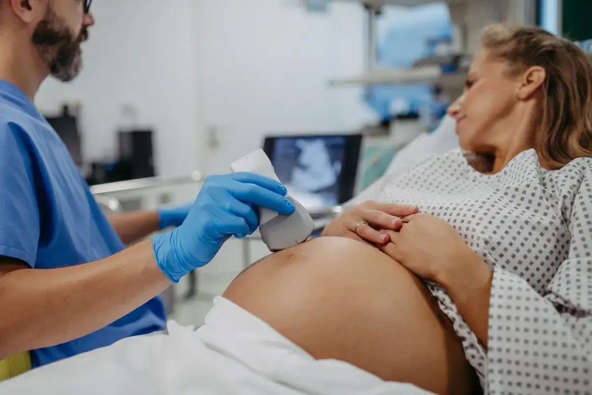 Lekarz wykonuje USG brzucha ciężarnej, dbając o jej zdrowie i bezpieczeństwo dziecka. To ważny etap w trosce o szczepienie RSV w ciąży.
