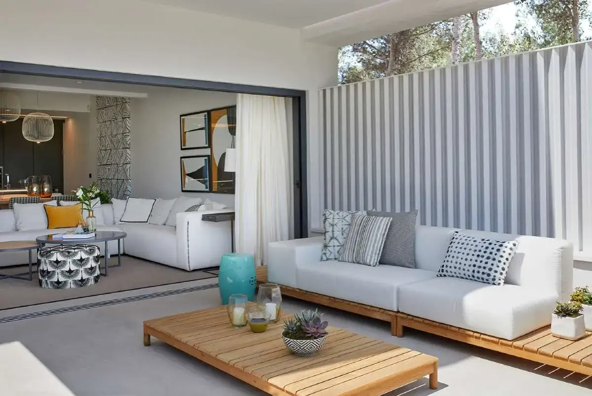 Elegante decoracion de casas con sofás blancos, mesas de madera y arte moderno. Un espacio exterior acogedor.