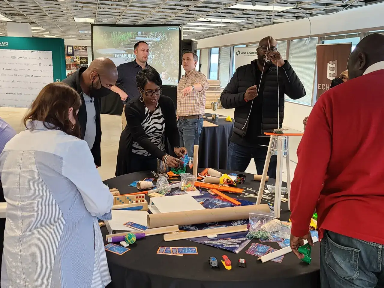 Des participants engag&eacute;s dans une activit&eacute; de groupe, construisant des objets avec des mat&eacute;riaux vari&eacute;s.