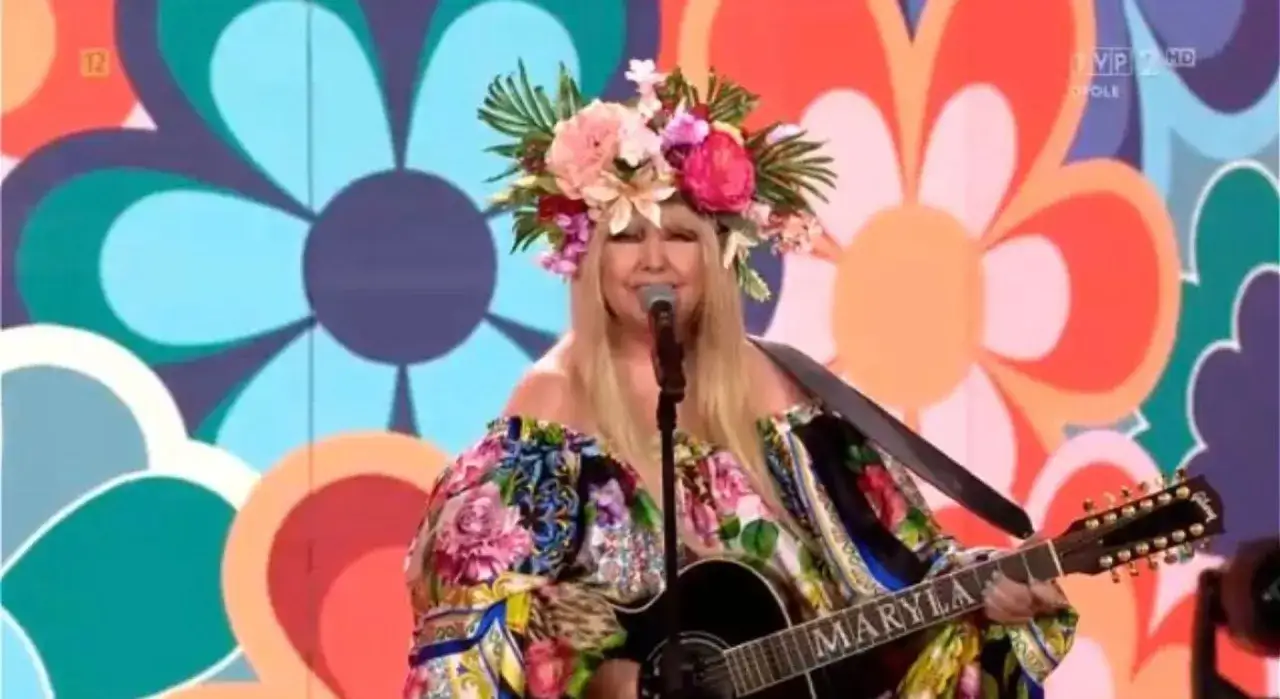 Maryla Rodowicz w kwiecistej kreacji i wianku śpiewa, grając na gitarze. Tło zdobią wielobarwne kwiaty, nawiązując do jej kultowych utworów.