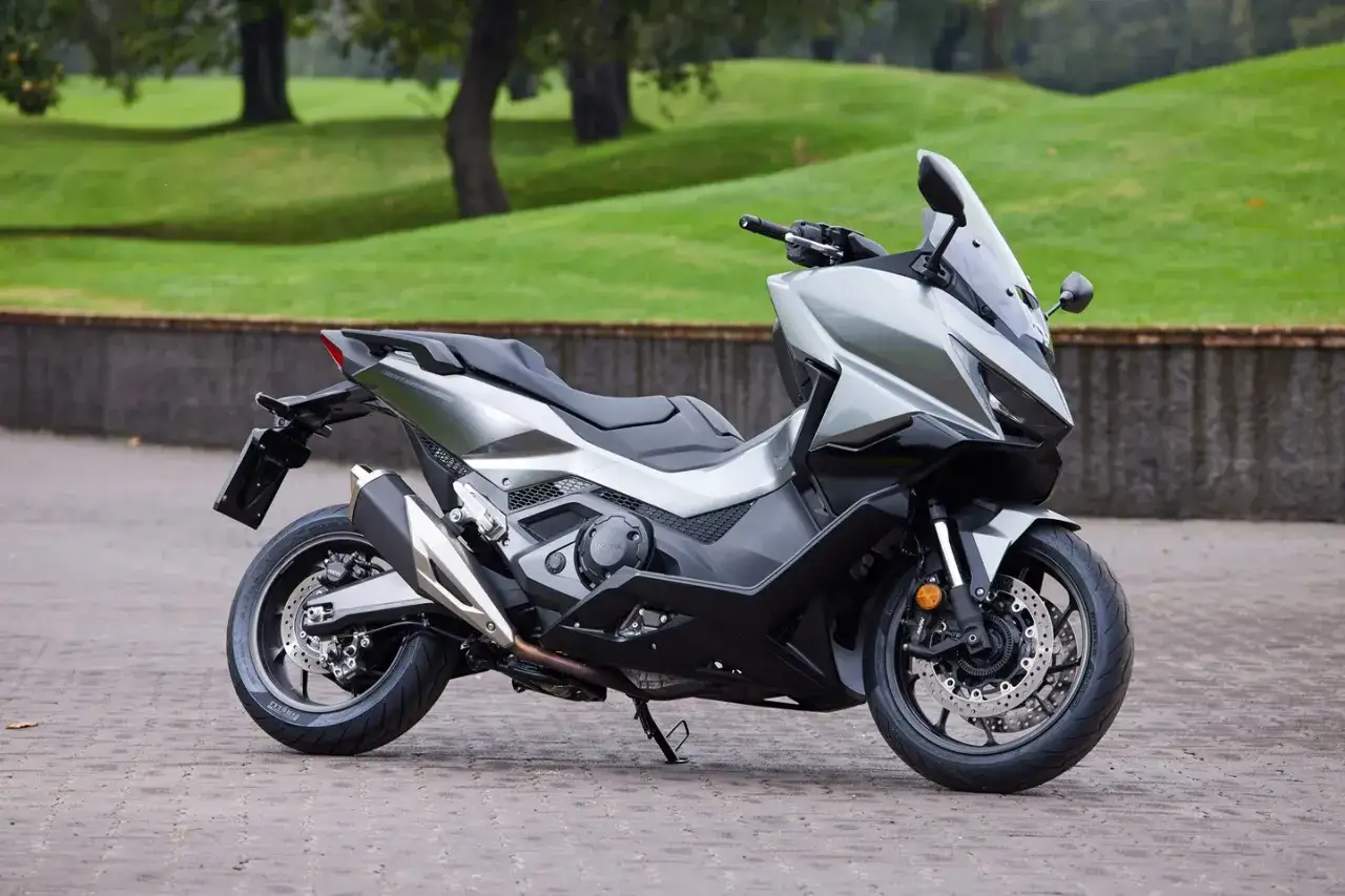 Honda Forza 750, un scooter deportivo plateado con líneas aerodinámicas, listo para la aventura. Consulta su ficha técnica.