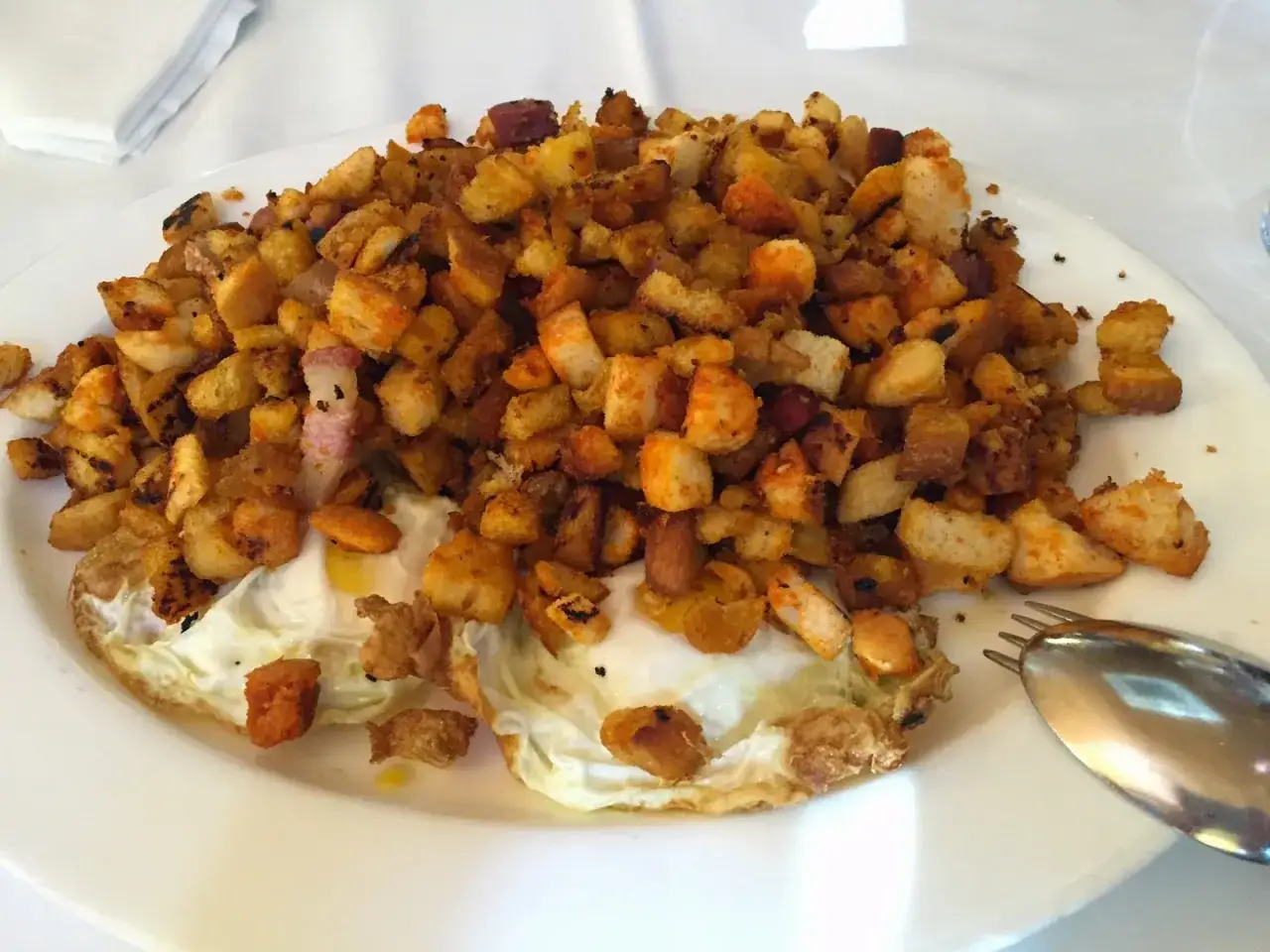 Plato de huevos fritos con patatas y pan crujiente, típico de las fotos de bar restaurante Casa Goyo.