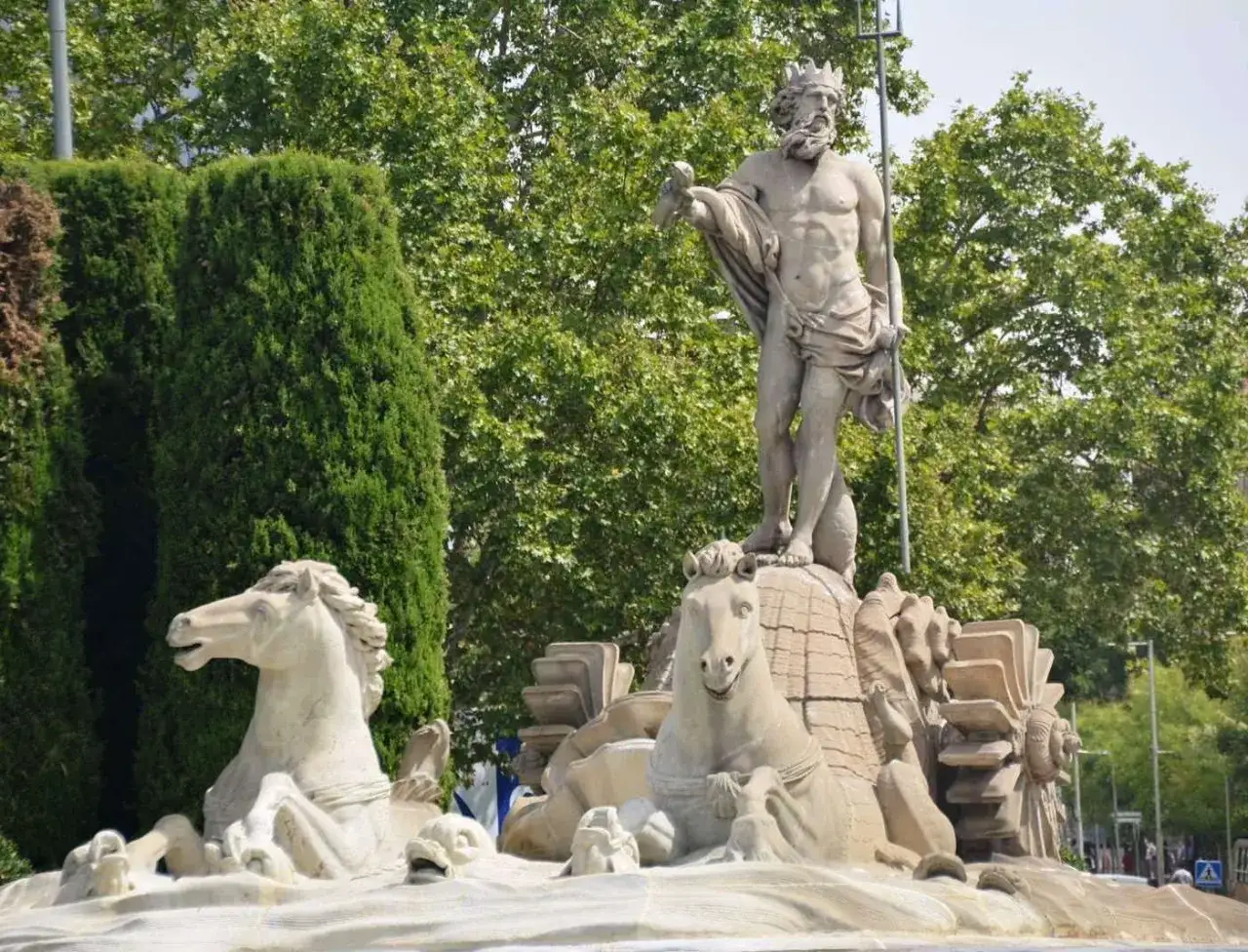 La fuente de Neptuno, con el dios del mar coronado, rodeado de caballos marinos y vegetación exuberante.