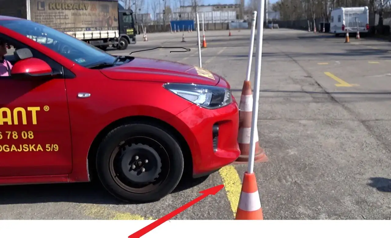 Czerwony samoch&oacute;d na placu manewrowym. Zastanawiasz się, ile błęd&oacute;w można zrobić na egzaminie praktycznym na prawo jazdy?