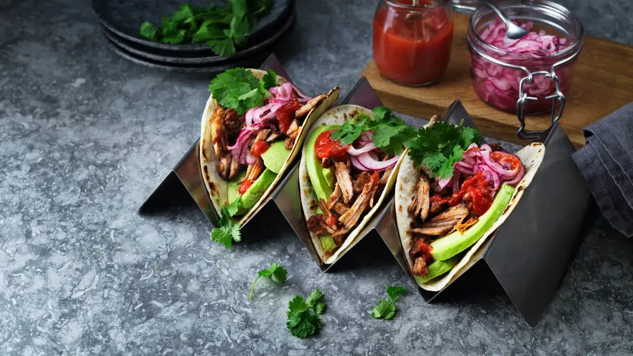 Tre läckra pulled pork tacos med avokado, rödlök och koriander. Perfekt för en smakrik måltid.