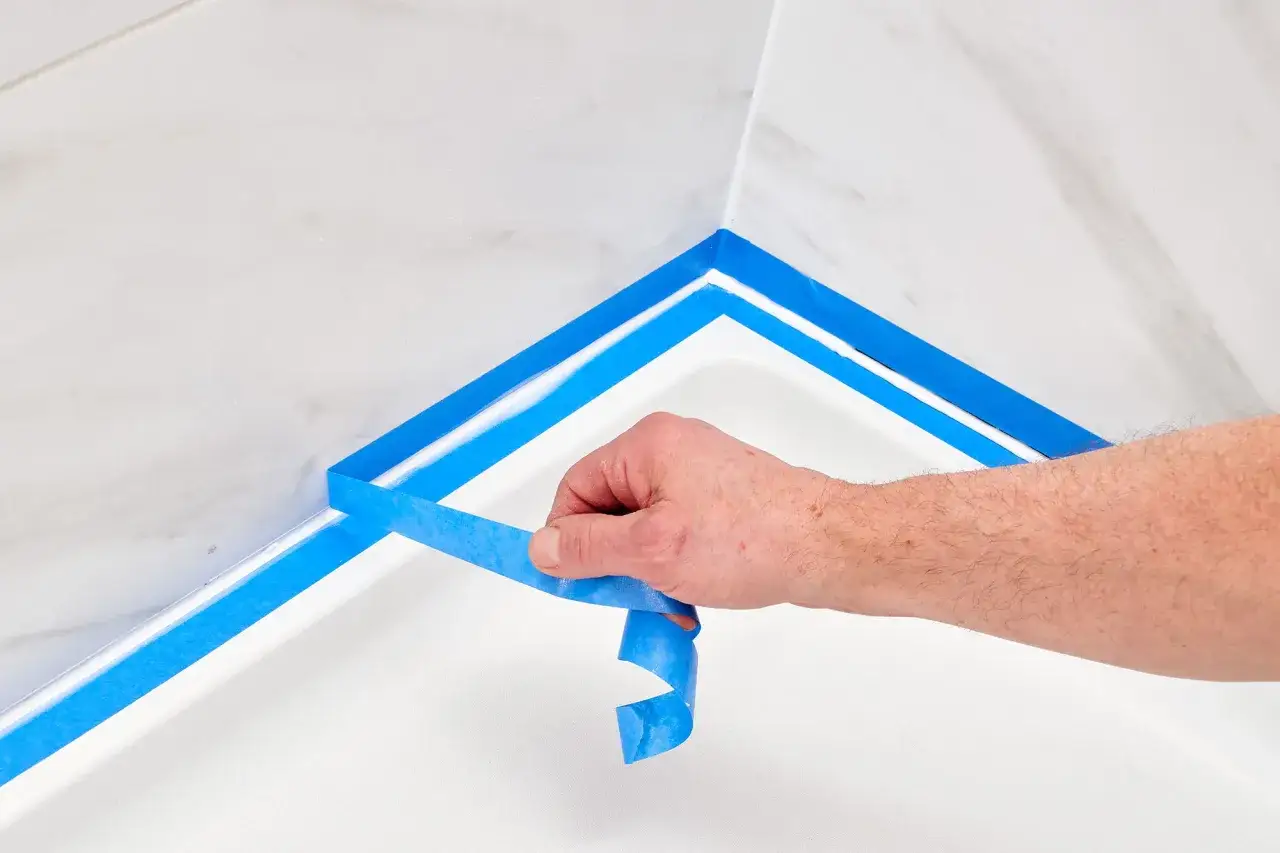 Hand tape an Eckfuge in der Dusche ab, um die Fugen zu versiegeln.