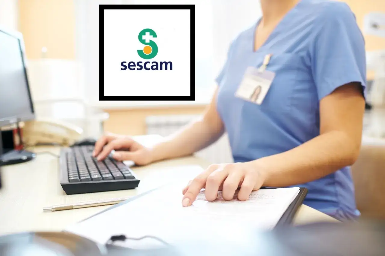 Persona trabajando en ordenador, con logo de Sescam. Ideal para cursos baremables auxiliar administrativo Sescam.