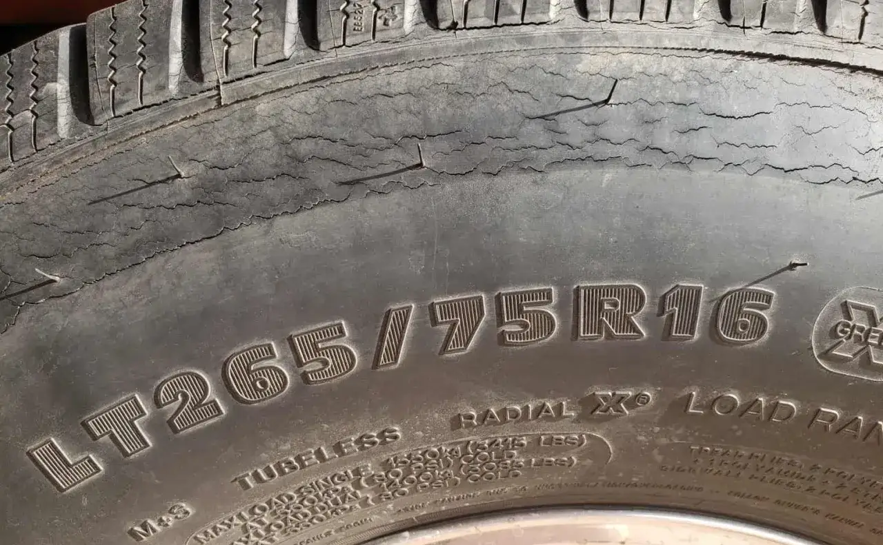 Popękane opony z boku, z widocznymi licznymi pęknięciami na powierzchni. Widać rozmiar LT265/75R16.