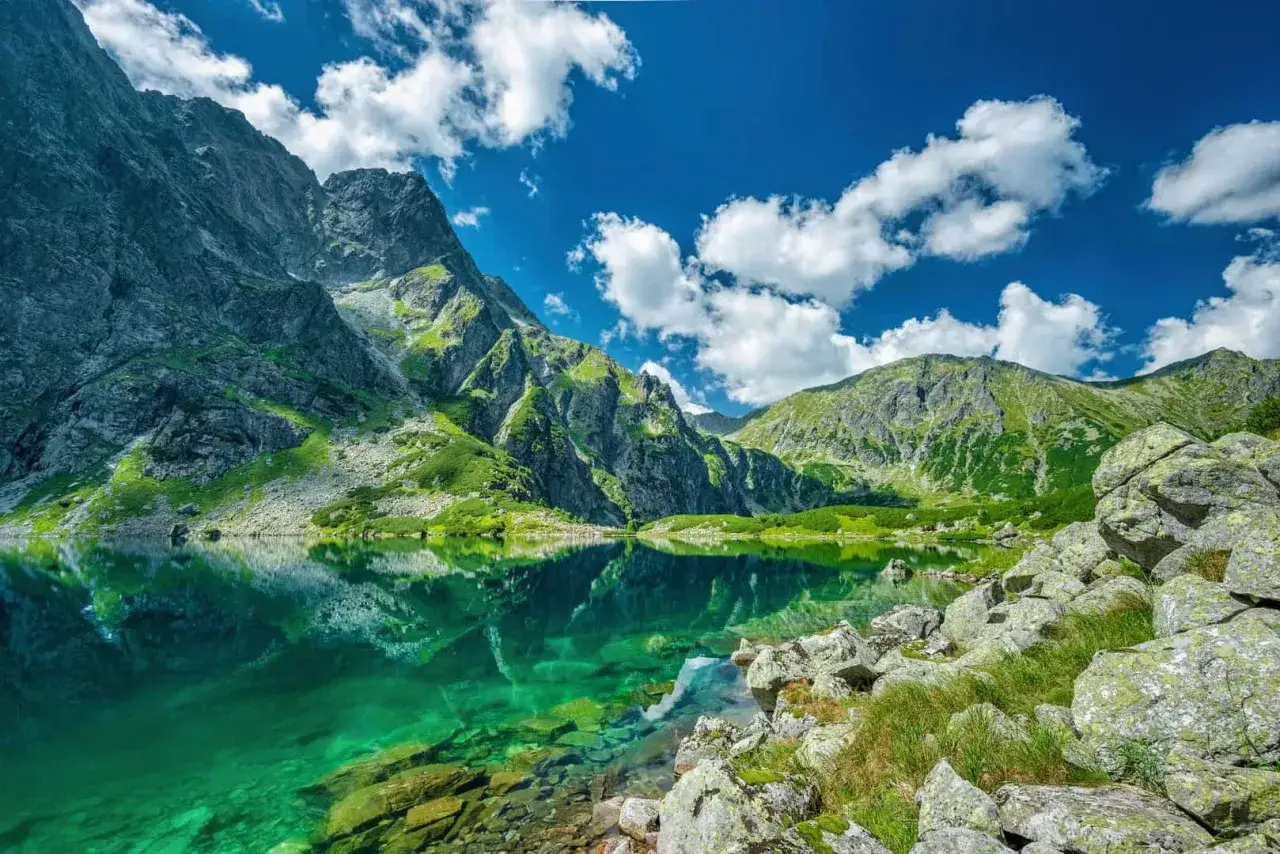 Piękna pogoda w Tatrach. Jezioro Morskie Oko odbija skaliste szczyty i błękitne niebo z chmurami.