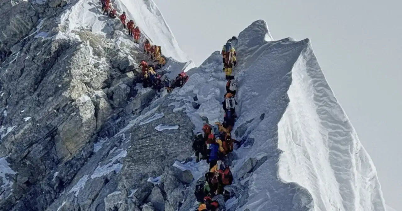 Korek na Mount Everest. Tłum ludzi w kolorowych kurtkach wspina się po skalistym zboczu.