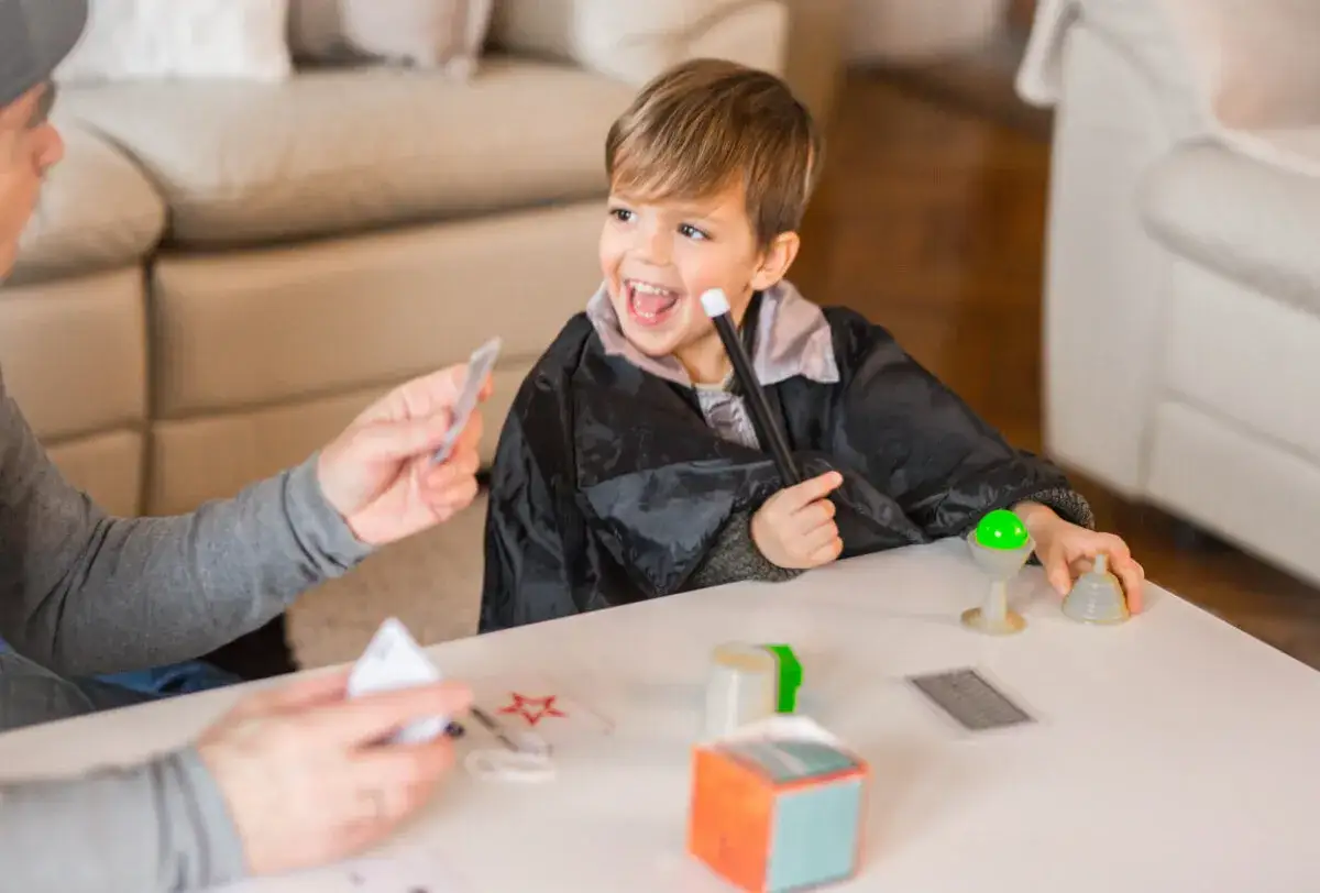 Niño emocionado con varita mágica y capa, aprendiendo trucos de magia para niños de 3 a 6 años.