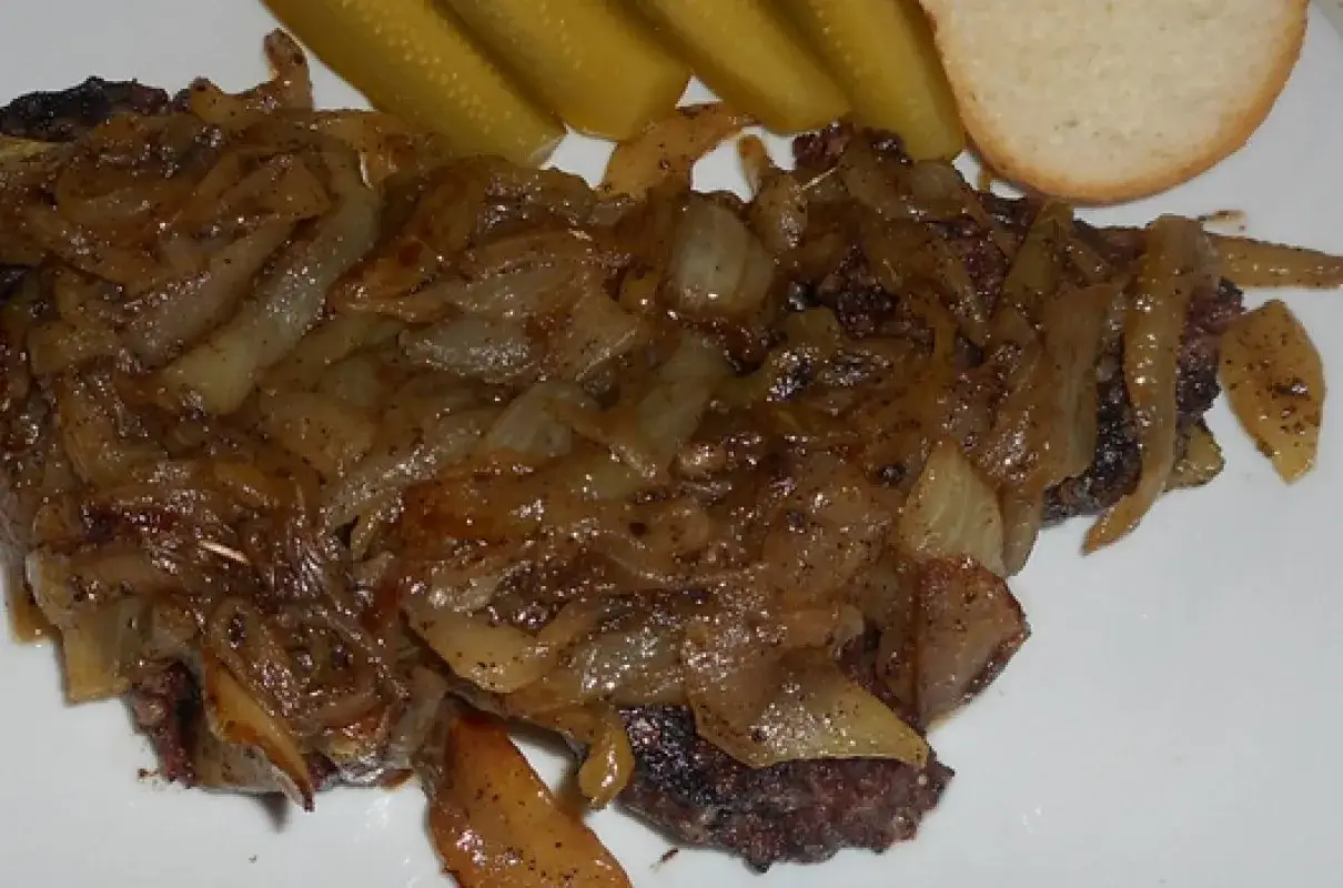 Kaszanka z patelni duszona z cebulką, podana z og&oacute;rkami kiszonymi i kromką chleba. Pyszne danie na szybko.