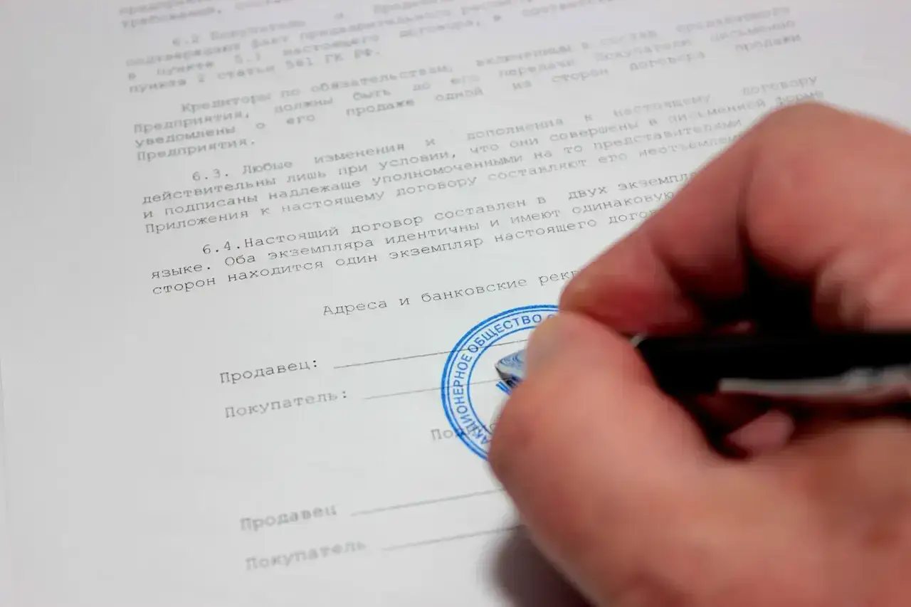 Szukanie pracy z wpisem do KRK, zatrudnienie z wyrokiem w życiorysie. Dłoń stawia pieczęć na dokumencie, symbolizując trudności w znalezieniu zatrudnienia.