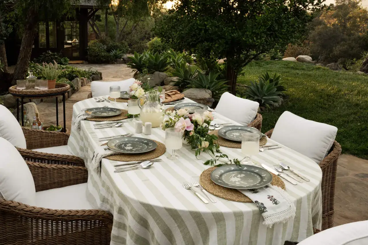 Une belle table est prête à être mise en extérieur, avec des assiettes fleuries, des verres remplis de limonade et un bouquet de fleurs fraîches.