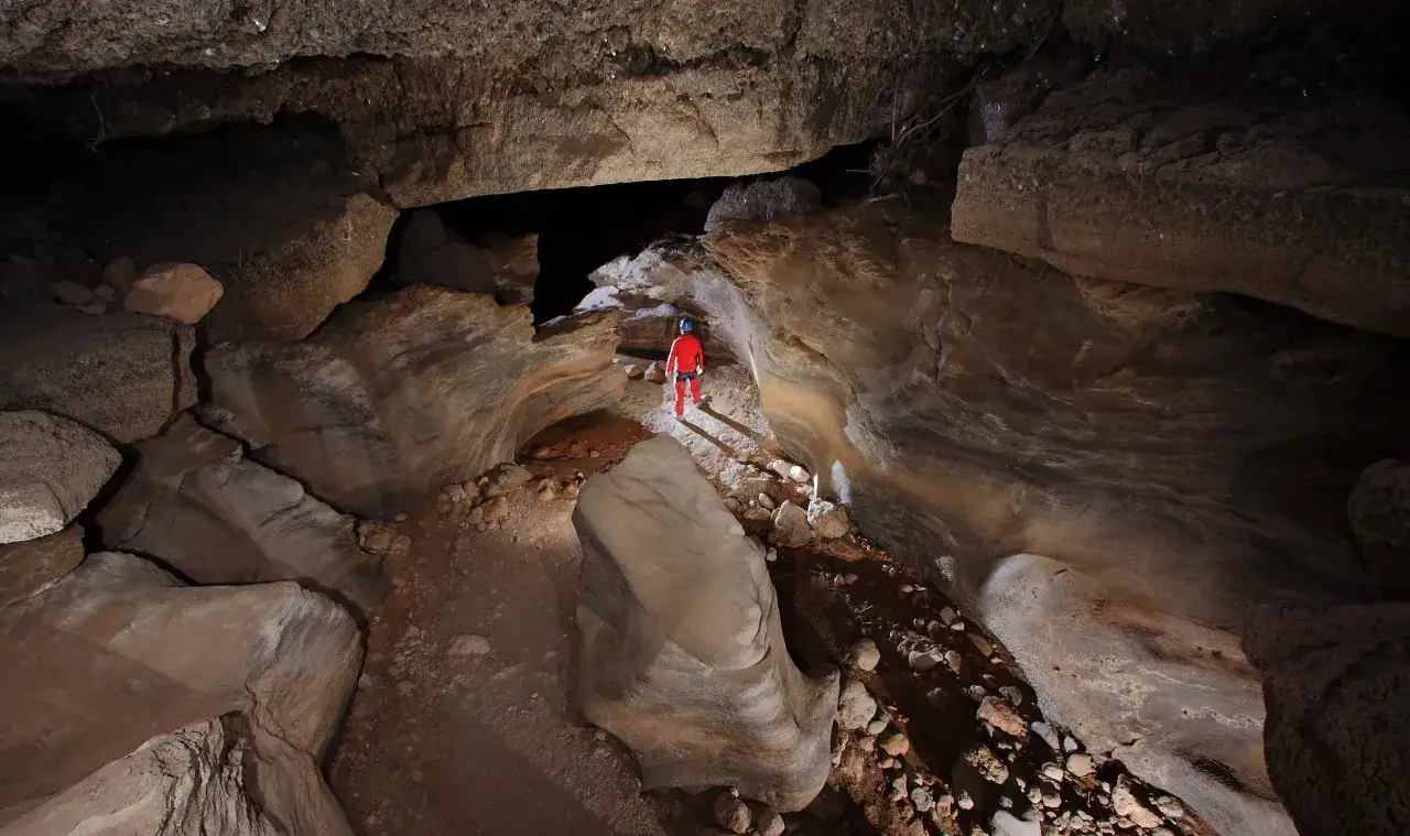 Explorador en el karst en yesos de Sorbas, rodeado de formaciones rocosas y un arroyo subterr&aacute;neo.