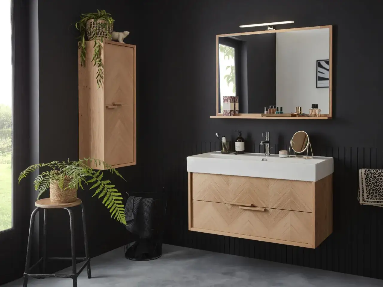 Une salle de bain moderne avec des meubles en bois clair, un lavabo blanc et un miroir. Une plante verte apporte une touche de nature. Inspiration salle de bain.