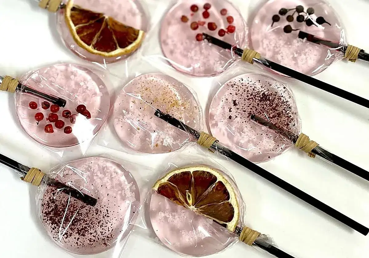 Pirulís rosados con rodajas de limón, bayas y especias. Usos de la sal en repostería creativa.