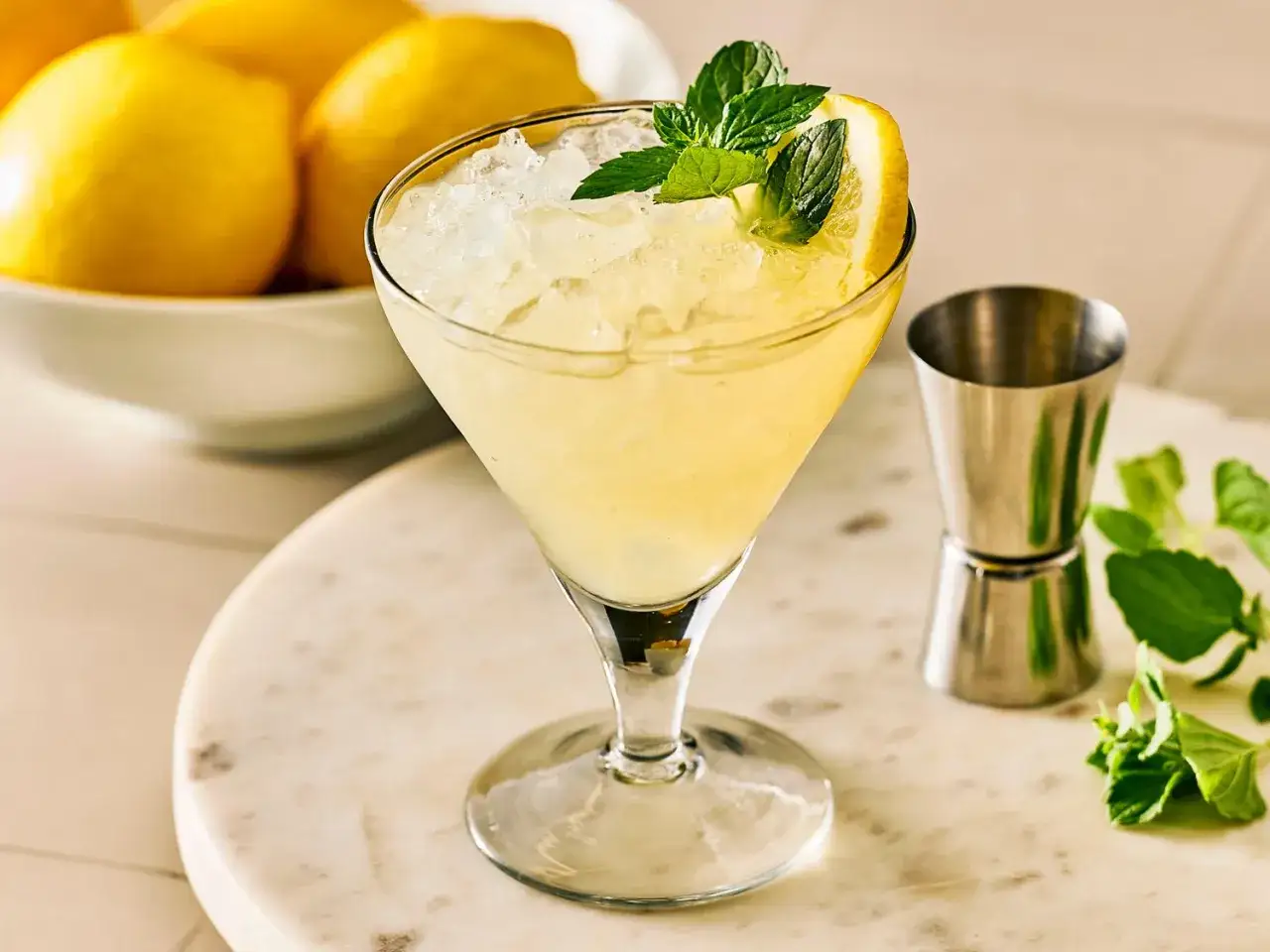 Orzeźwiający drink z cytryną i miętą, idealny do letnich przepisów na proste drinki. Obok kieliszka stoi miarka barmańska.