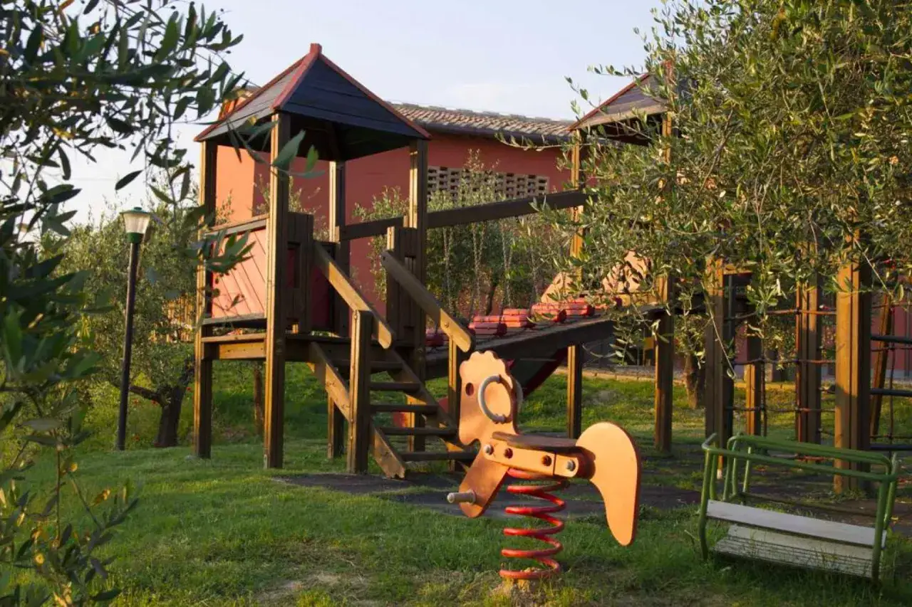 Un parco giochi in fattoria, perfetto per dormire in fattoria con bambini. Giochi in legno, altalene e un cavalluccio a molla tra gli ulivi.
