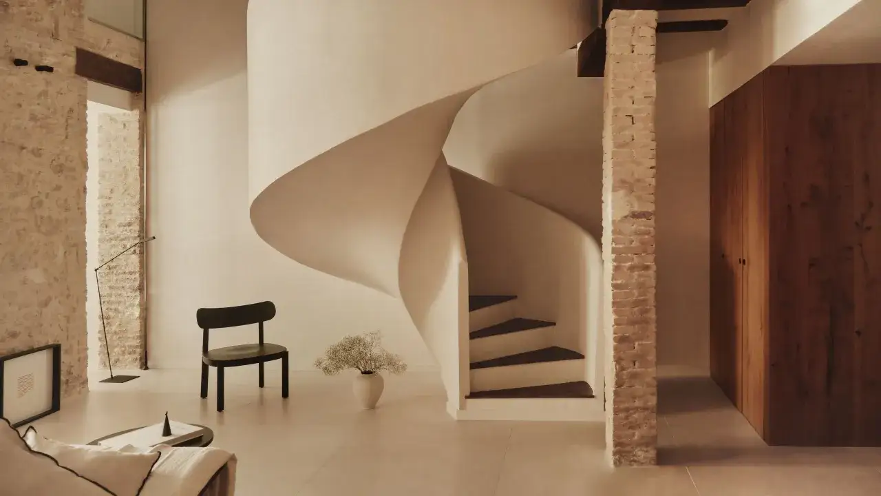 Escalera de caracol moderna, un ejemplo de los diversos tipos de escaleras de obra, con pelda&ntilde;os de madera oscura y paredes de ladrillo expuesto.