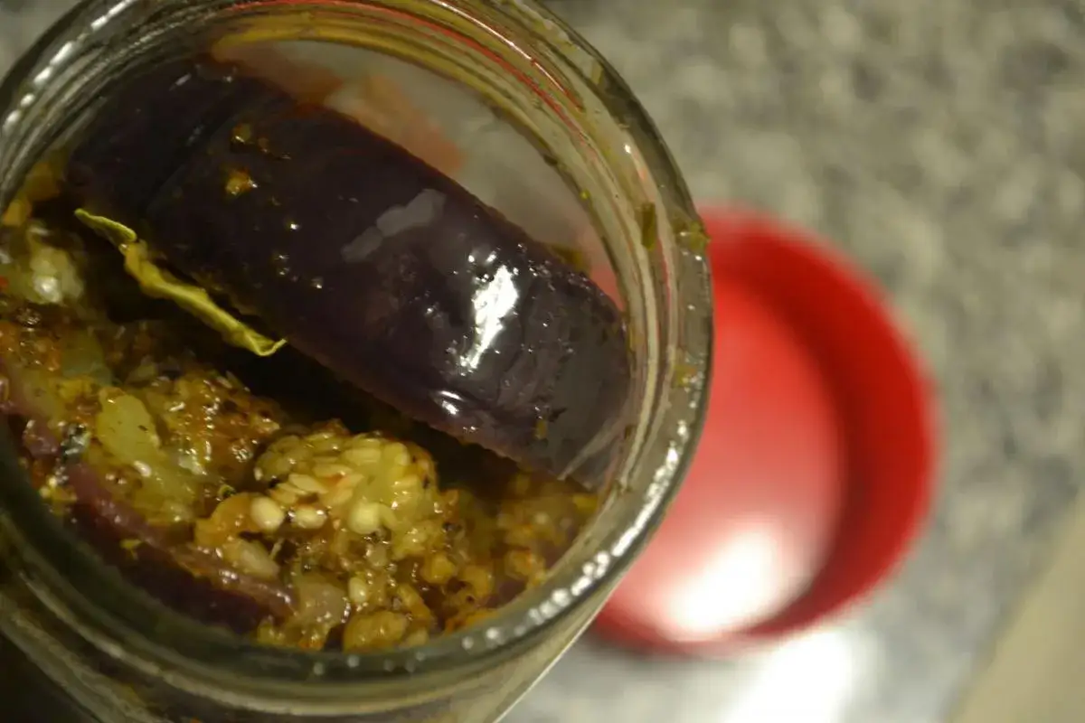 Berenjenas en escabeche, un manjar casero en un frasco de vidrio, con trozos de berenjena morada y especias.