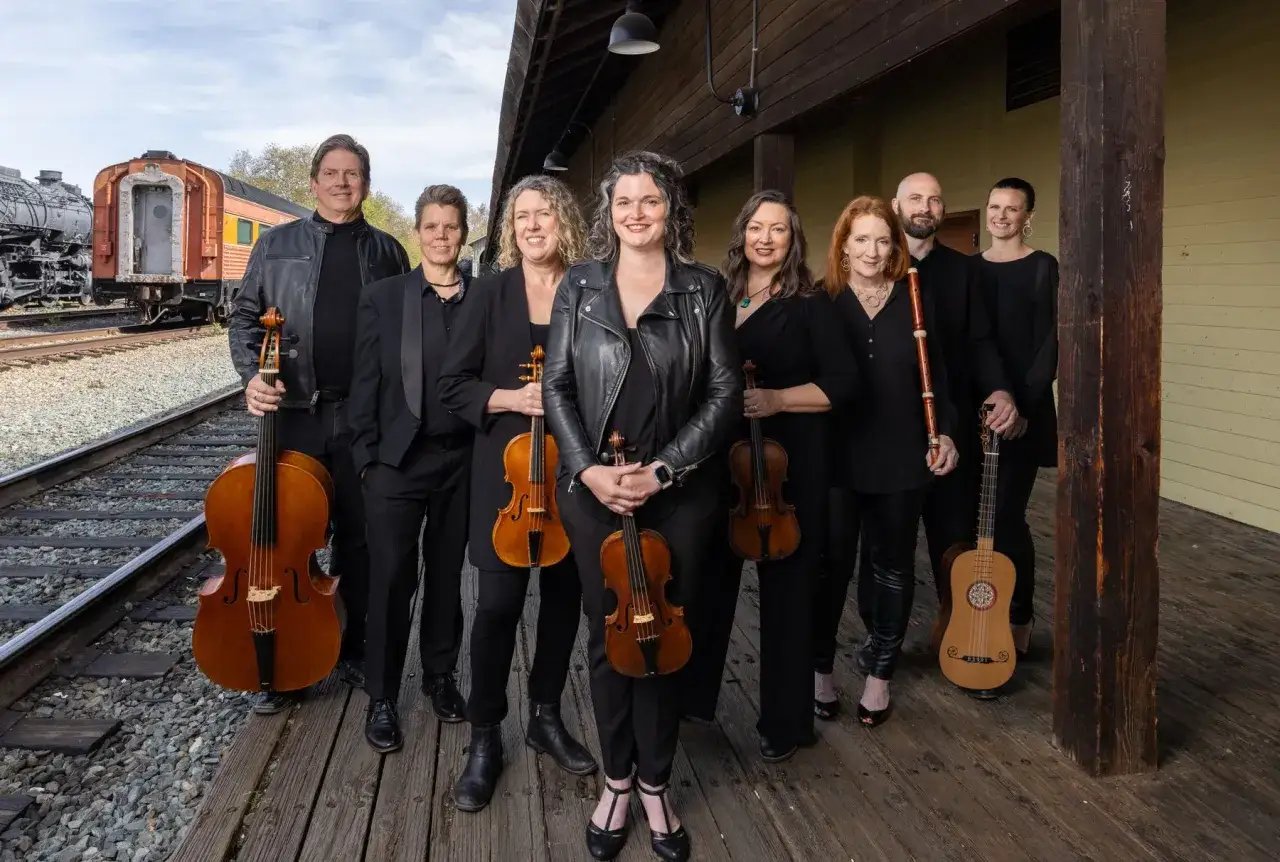 Zespół muzyczny przygotowuje się do wykonania concerto grosso na tle starych pociągów.