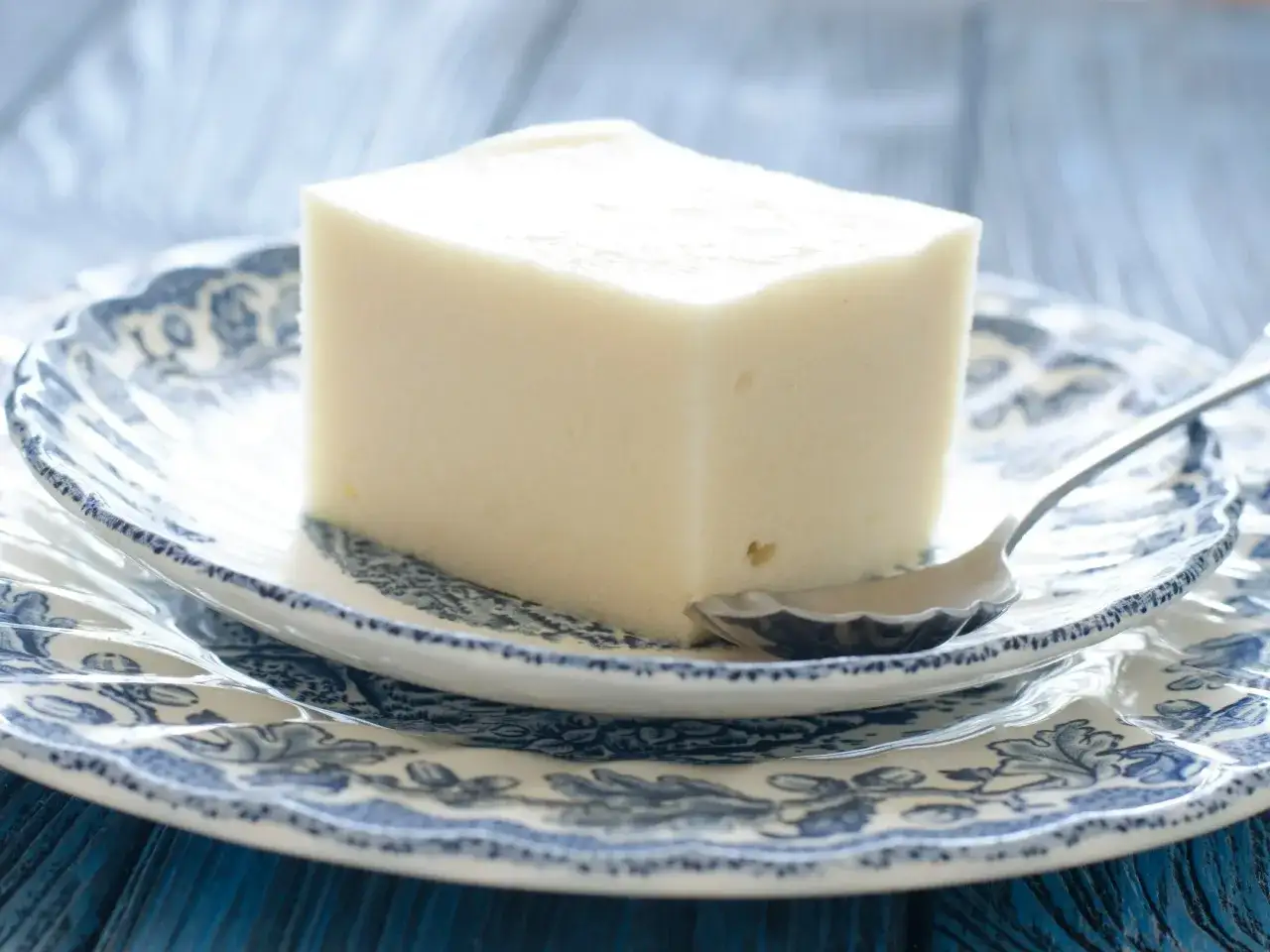 Kostka delikatnego deseru na talerzyku z niebieskim wzorem. Idealny na letnie popołudnie, gdy szukasz lekkiego deseru. Zupa nic przepis na wyciągnięcie ręki!