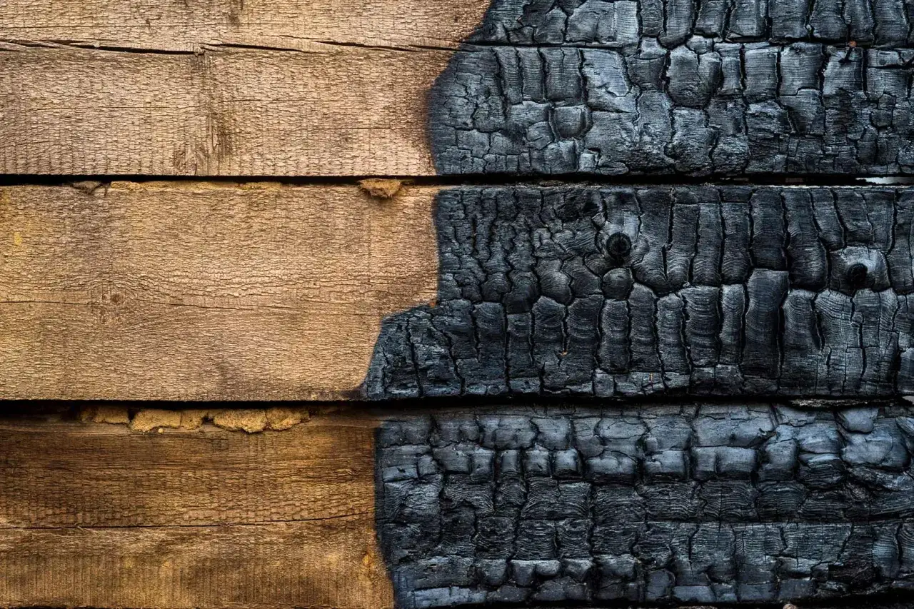 Tavole di legno, metà naturali e metà con la texture profonda del legno bruciato giapponese, che evoca un antico rituale.