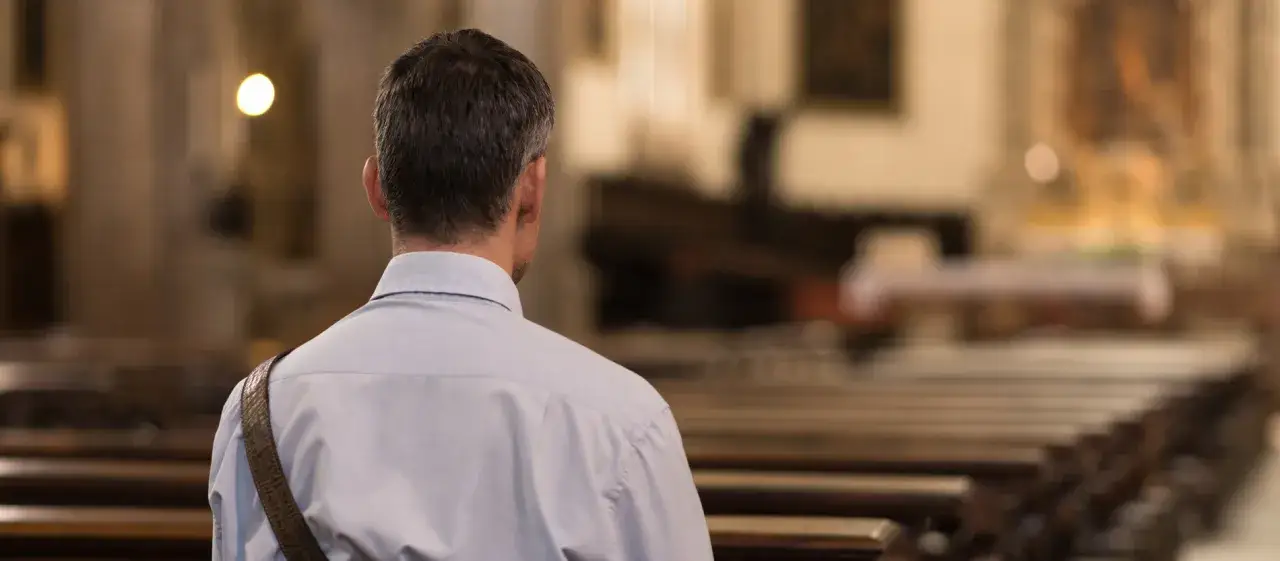 Mann in Kirche, nachdenklich. Was macht einen Mann aus? Innere Einkehr, Stärke, Glaube.