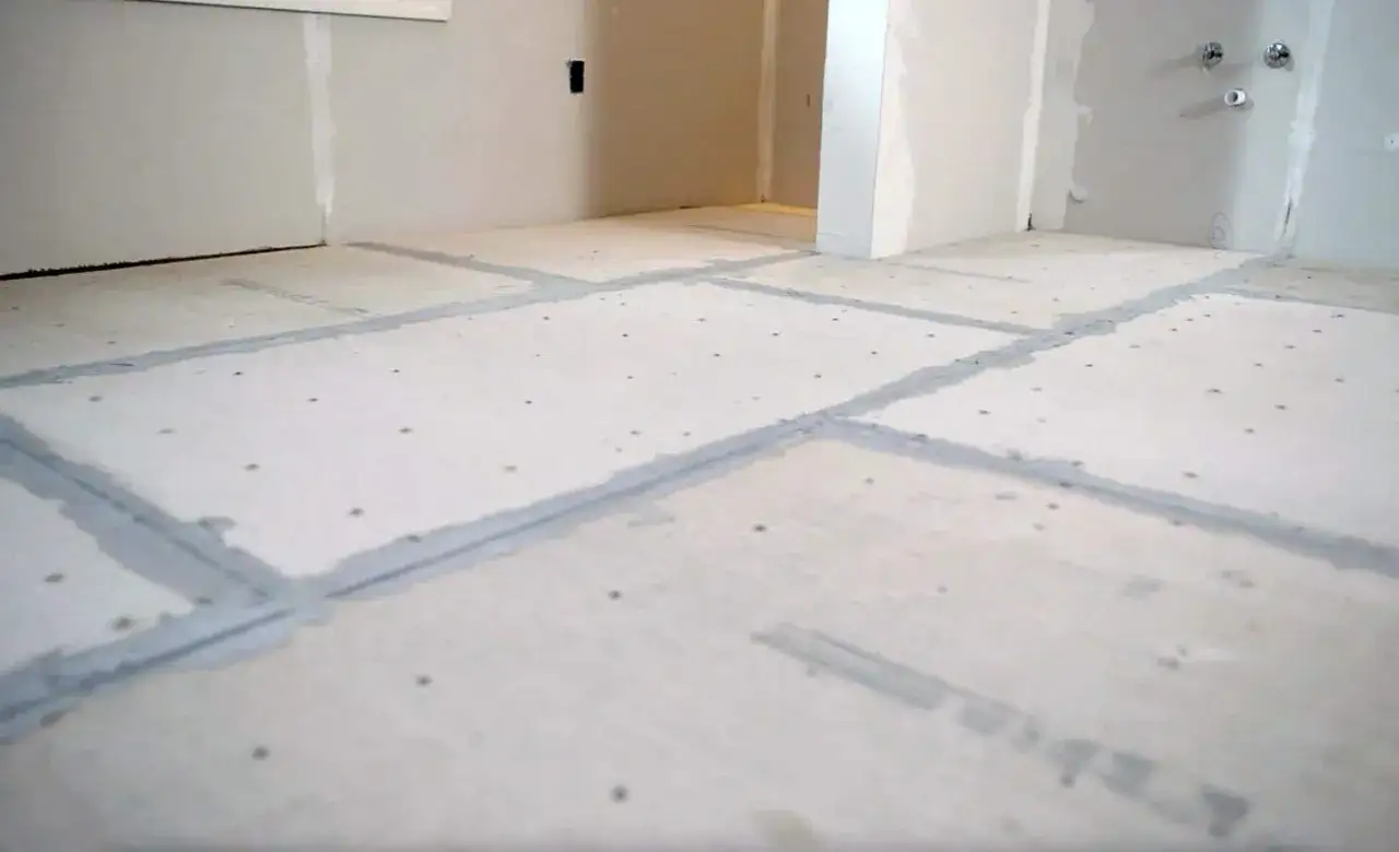 Concrete board installed on a floor, with seams taped and mudded. This shows a step in how to install concrete board for a tile project.