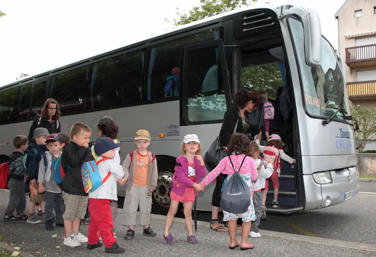 Des enfants attendent leur tour pour monter dans le bus. Le temps de conduite chauffeur de bus sera bientôt terminé pour eux.