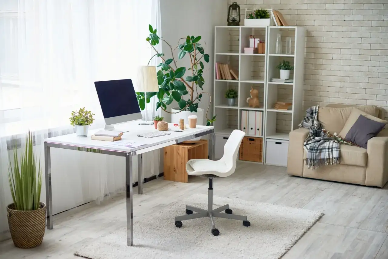 Bureau lumineux avec ordinateur, plantes et fauteuil confortable. Idéal pour le télétravail raison médicale.