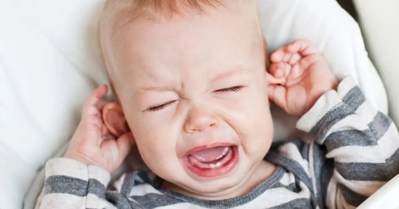 Maluch płacze, zasłaniając uszy. To pewnie gorączka przy ząbkowaniu.