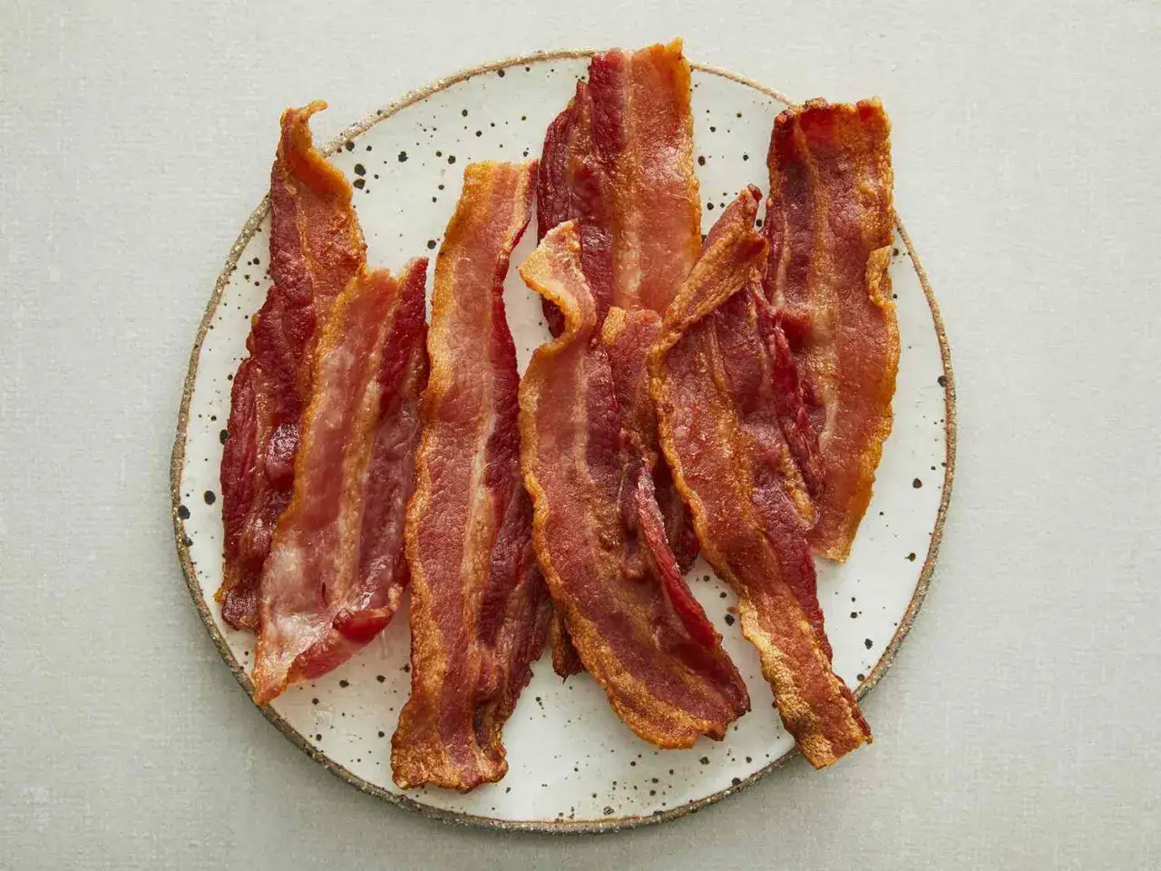 Krispigt stekt bacon i airfryer, serverat på en tallrik. Perfekt för en lyxig frukost.